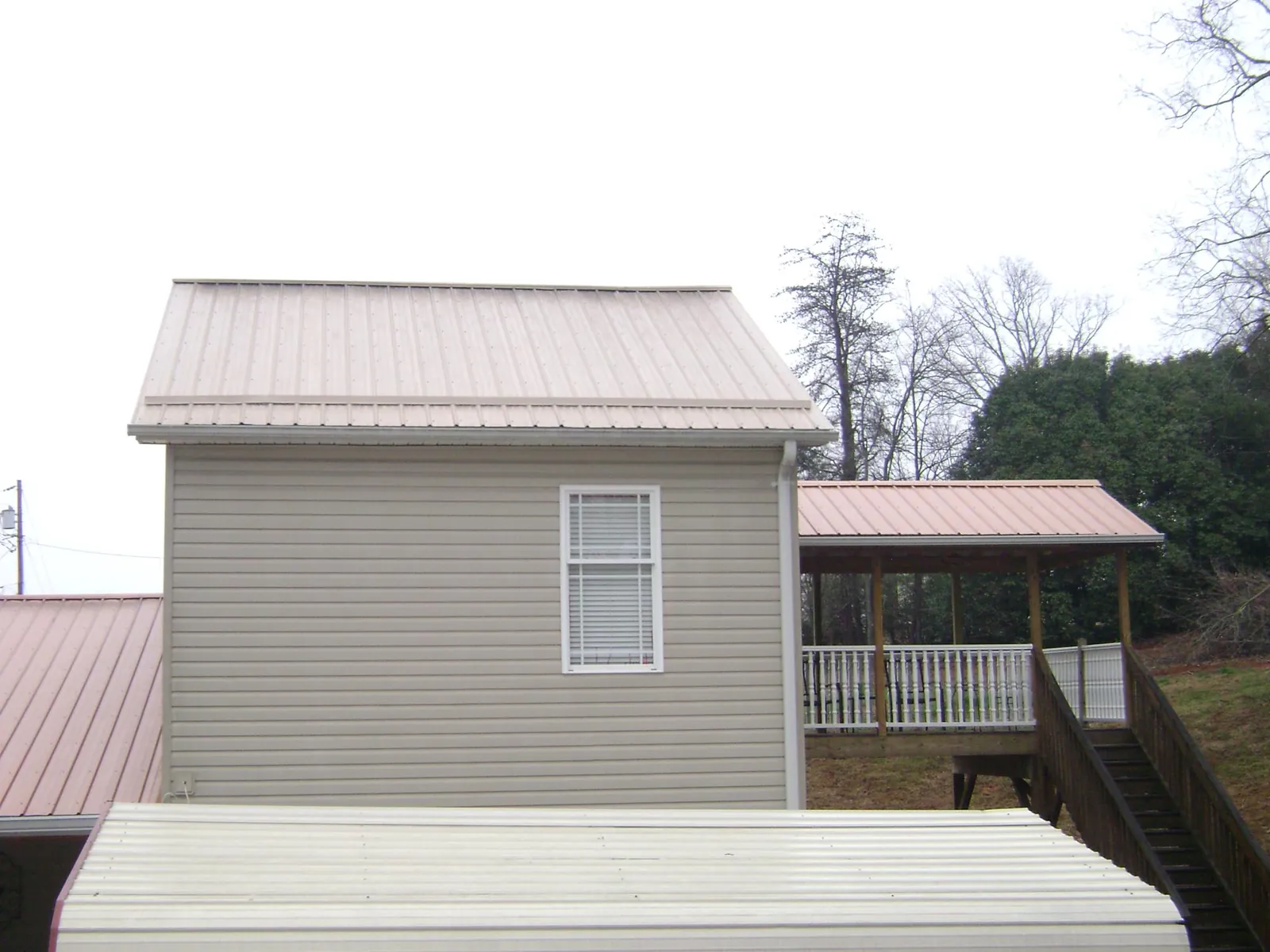 Tan metal roofs on a two story addition and attached porch, from a Roof Replacement job in Maxwell