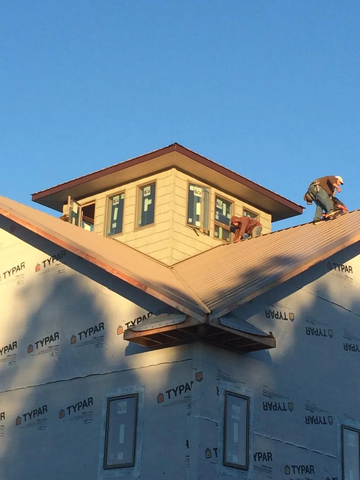 Roofers working around a rooftop cupola on a new metal roof at sunset — Roof Waterproofing in Maxwell by Roofing Brothers